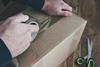 Person taping up cardboard box for postage