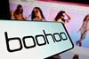 Boohoo logo on phone against background of Boohoo website showing models