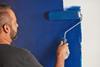 Man painting wall with blue paint