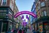 Entrance to Carnaby Street in London decorated with neon pink signs and lights