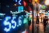 Stock market listings shown through the window of a busy street by night