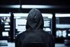 Hacker in a dark room with computer screens