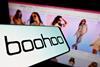 Phone with Boohoo logo held in front of a screen showing Boohoo website