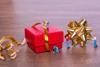 Toy-figures-wrapping-up-an-oversized-Christmas-present-with-ribbons index