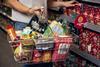 Customer carrying basket of groceries in Morrisons