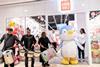People drumming and someone in a penguin outfit outside Miniso store, London
