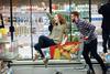 Man pushing woman on shopping trolley