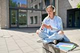 Student sitting outside on campus using smartphone