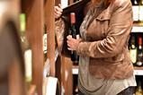 Woman shoplifting a bottle of wine, shown from neck down