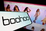 Boohoo logo on a phone in front of a website showing models