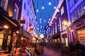 London-street-with-people-eating-outside-by-night
