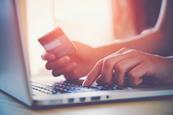 Close up on one hand typing on a laptop and the other holding a credit card