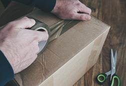 Person taping up cardboard box for postage