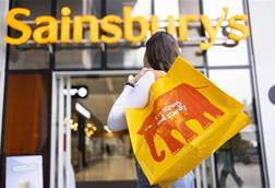 Woman holding Sainsbury's reusable bag and heading into Sainsbury's store