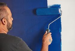 Man painting wall with blue paint