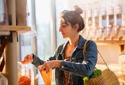 Woman in a shop filling a brown paper bag with cereal