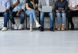 Six people queuing for job interview, seated, shown from head down