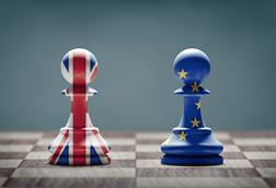 Two pawns on a chessboard, one painted with the Union Jack and one with the EU flag