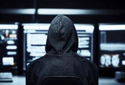 Hacker in a dark room with computer screens