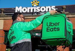 Uber Eats rider holding delivery bag outside Morrisons store