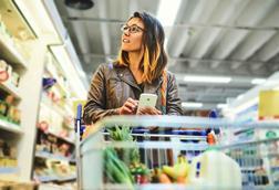 Woman-shopping-in-supermarket-and-looking-at-phone