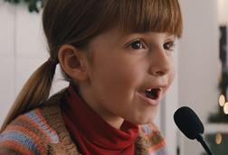 Still from Sainsbury's 2023 Christmas TV advert showing girl speaking into tannoy