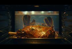 Still from Morrisons Christmas advert showing Union Jack oven gloves removing a turkey from the oven