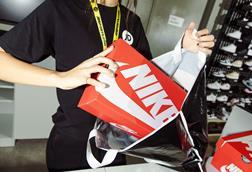 Store worker putting Nike trainers in JD Sports bag