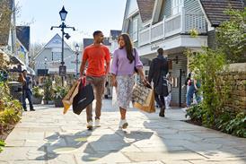 Exterior of Bicester Village showing shoppers walking past Farmshop restaurant