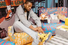 Young black man trying on trainers while seated in Foot Locker Brixton store