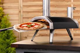 Ooni-branded pizza oven, shown in a garden with pizza inside it