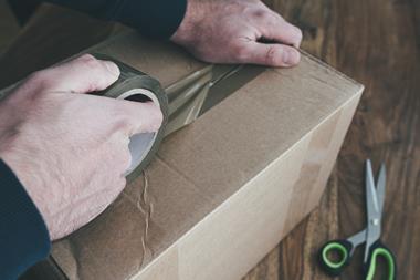 Person taping up cardboard box for postage