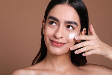 Model applying Feelunique skincare to her face