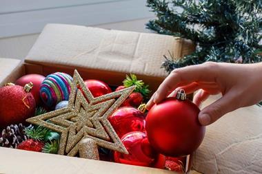 Hand putting Christmas decorations away in a cardboard box
