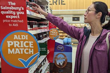 Woman shopping in Sainsburys next to an Aldi Price Match sign