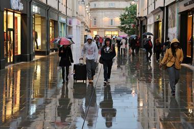 Shoppers walking in rain down Bath high street