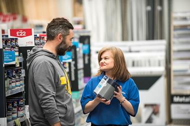 Wickes customer talking to store assistant holding tin of paint