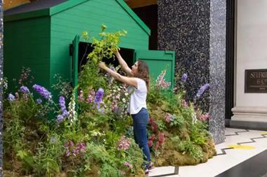 Woman arranging flowers outside green shed at Selfridges gardening centre