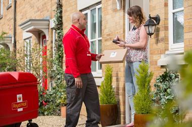 Royal Mail delivery worker handing package to customer at front door