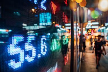 Stock market listings shown through the window of a busy street by night