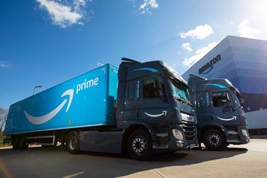 Two Amazon electric HGVs outside and Amazon-branded building