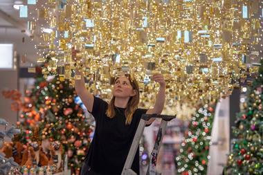 Employee in John Lewis hanging up Christmas decorations