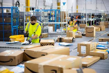 Socially distanced Amazon workers processing packages in a fulfilment centre, wearing masks