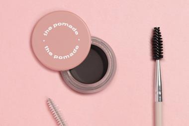 Boohoo beauty products on a pink background including The Pomade, the Brow Gel and a double-sided make-up brush