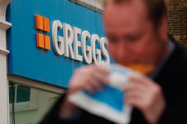 Man eating a pasty outside a Gregg store