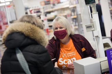 Masked Sainsbury's colleague serving a customer