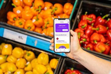 Customer holding phone in supermarket with Nectar app on screen