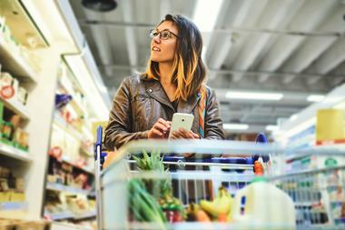 Woman-shopping-in-supermarket-and-looking-at-phone