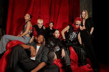 Seven male and female models wearing Hugo Boss clothing on a red sofa
