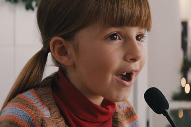 Still from Sainsbury's 2023 Christmas TV advert showing girl speaking into tannoy